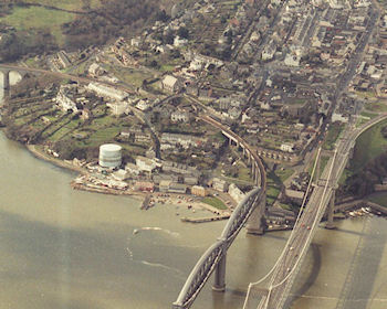 Taken from above the Tamar Bridge and looking westwards, this photo shows most of the town centre, spanning from Fore Street on the right to Coombe on the left. To anyone familiar with Saltash today, the most noticable features are the big gas tank on the foreshore where the Sailing Club is now, the lack of houses on the far side of the Coombe, the big old Baptist Chuch, and the roundabout where the tunnel entrance now is at the end of the Tamar Bridge.